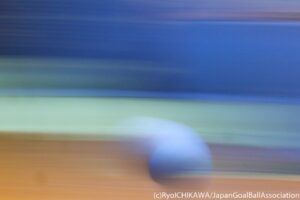 A goalball is pictured in a blur as it flies through the air