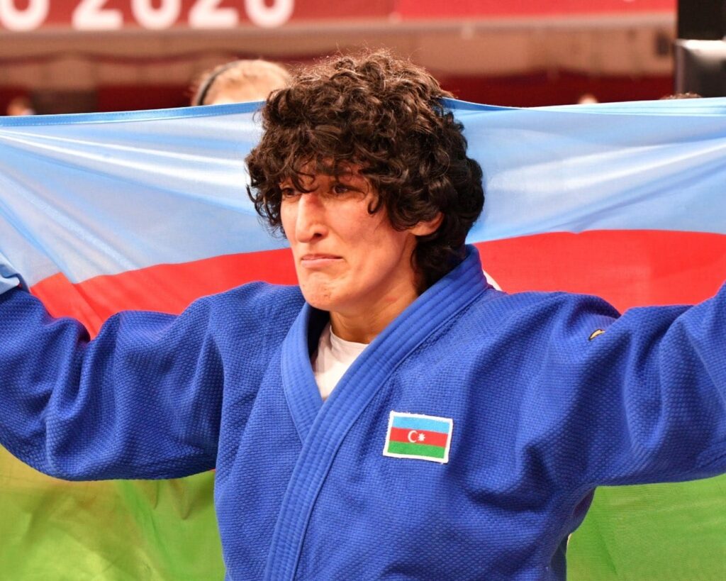Khanim Huseynova holds up an Azerbaijan flag around her shoulders and looks very emotionall