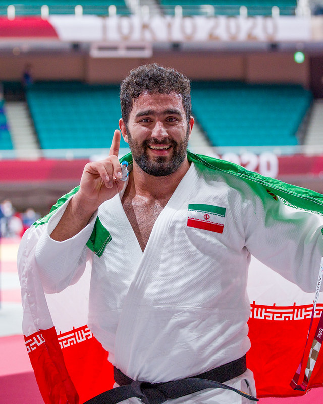 Mohammed Kheriollahzadeh makes a No.1 symbol with his finger whilst holding the flag behind his shoulder